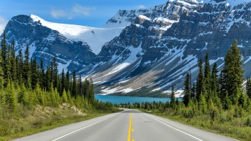 Icefields Parkway extending towards Bow Lake with Crowfoot Mountain in the background in Canada in April.